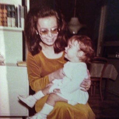 En lite oskarp bild av en liten flicka i sin mammas famn på 1960-talet.