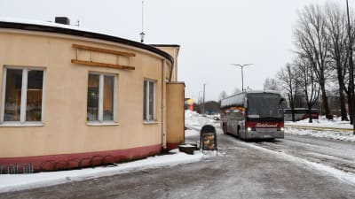 En buss i slasket utanför en stor gul byggnad.