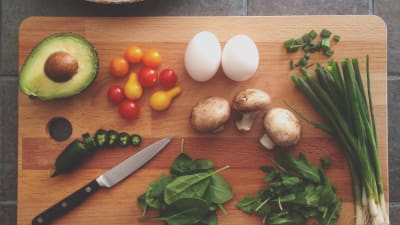 Grönsaker och ett par ägg på ett skärbräde av trä