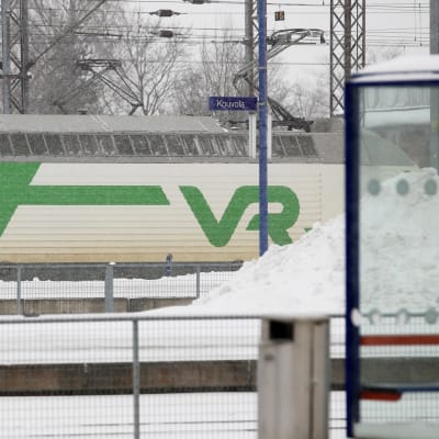 Tåg åker förbi snöig tågstation