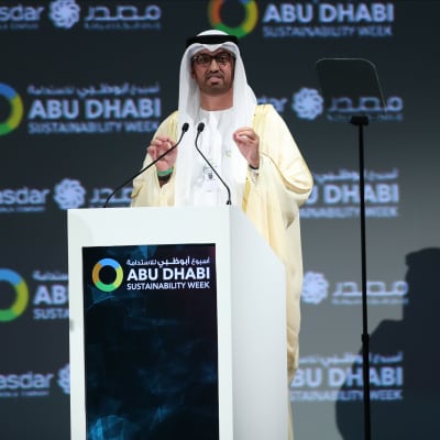 Sultanen Ahmed Al Jaber iklädd en vit kandura står och talar på ett evenemang.