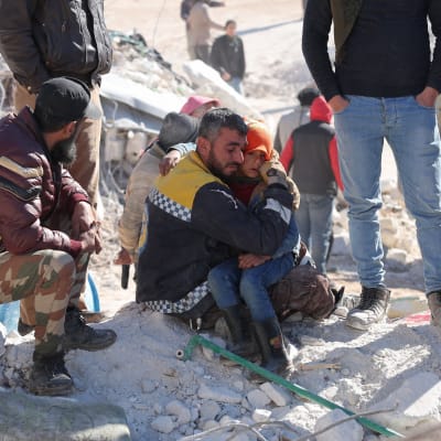 En syrisk medlem i biståndsgruppen De vita hjälmarna tröstar ett barn. 