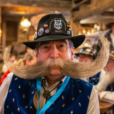 En man med stor mustasch och en hatt på huvudet. Han är en av deltagarna i skägg-OS i den tyska staden Eging am See i oktober, 2021.