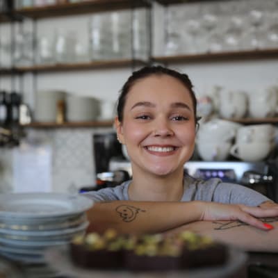 Nainen hymyilee kahvilassa