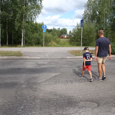 Isä ja poika ylittävät tien pojan koulumatkalla