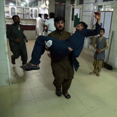 Mies kantaa haavoittunutta sairaalan käytävällä