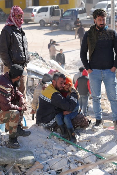 En syrisk medlem i biståndsgruppen De vita hjälmarna tröstar ett barn. 