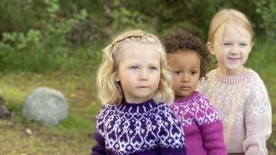 Tre flickor iklädda handstickade strömsötröjor i barnstorlekar