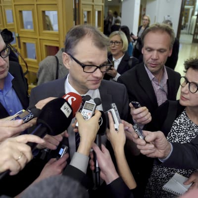 Statsminister Juha Sipilä omringad av journalister.