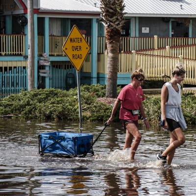 Två kvinnor plumsar genom vattnet på en översvämmad gata i Alabama efter att stormen Sally dragit fram i september.