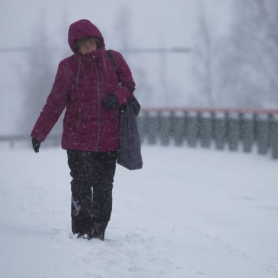Jalankulkija kävelemässä lumisella jalkakäytävällä.
