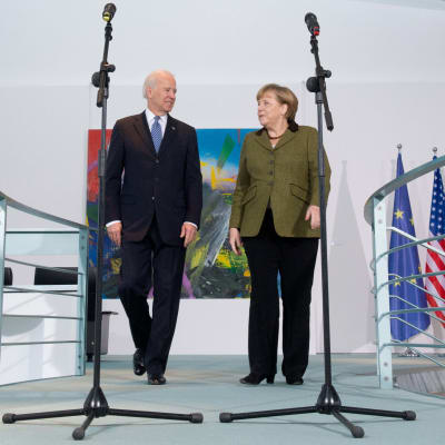 Joe Biden ja Angela Merkel mikrofonien takana. 