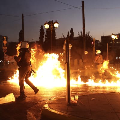 Grekiska poliser försöker undvika molotovcocktails som slängs mot dem i Aten under demonstrationen.