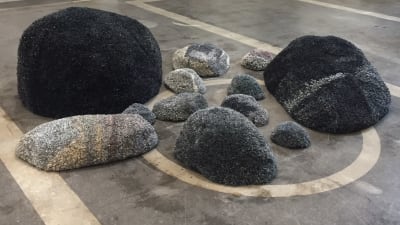 Skulpturala ryor som liknar stenar på golvet. 