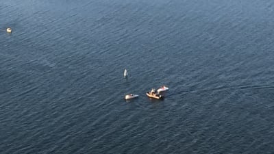 Helikopterbild av en motorbåt har kapsejsat i havet, flera båtar är på plats för att hjälpa.