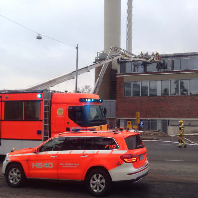 Uttryckningsfordon står parkerade utanför Mejlans sjukhus i Helsingfors. Brandmän jobbar med att släcka branden.