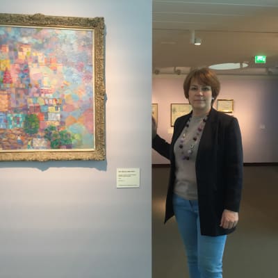 Kvinna står till höger om målning.