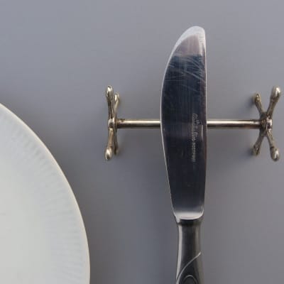 Närbild på en matkniv med eggen vänd inåt mot tallriken.