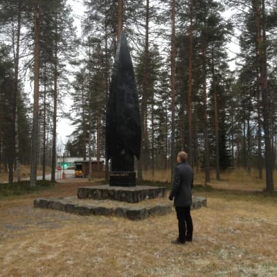 Minnesmärke med texten "Kollaa kesti" i Kontiolahti, Kontiolax. Kommundirektör Jere Penttilä beundrar.