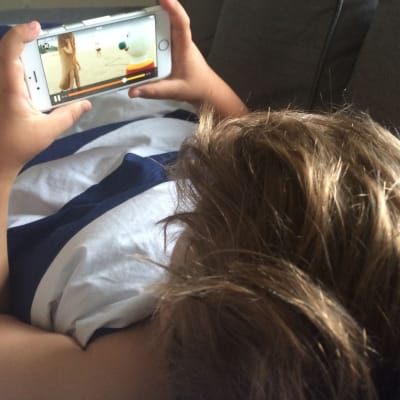 Pojke tittar på BUU-klubben på mobiltelefon