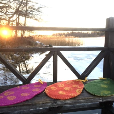 Tre tovade sittunderlag på en bänk med soluppgång i bakgrunden.