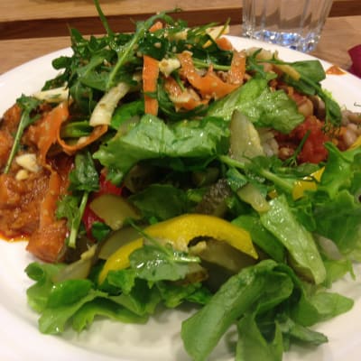 en tallrik fylld med grönsallad, böngryta och ytterlihare en vegansk röra som innehåller bland annat jordnötter.