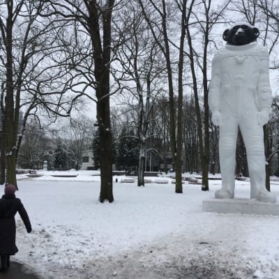 Isskulptur av apa klädd i austronautdräkt i en vintrig park i Rigas centrum