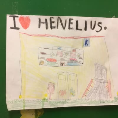 En teckning av ett barn. Bilden föreställer Henelius mataffär som inte längre finns. Texten lyder: I <3 (hjärta) Henelius. Bilden är klistrad på en grön skåpdörr.
