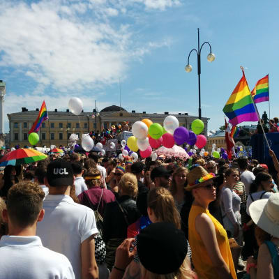 Människor med ballonger och regnbågsflaggor på Senatstorget.