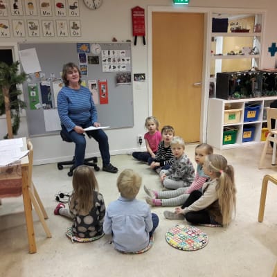 Morgonsamling på språkbadsdaghemmet Sälen. Barnen sitter i halvcirkel runt Marja Rönneberg. 