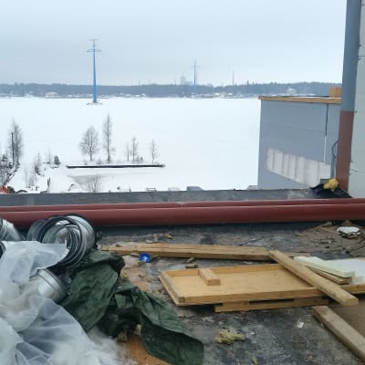 På taket till ett bygge, bräder, rör och plast på taket, utsikt mot Brändö sund i Vasa