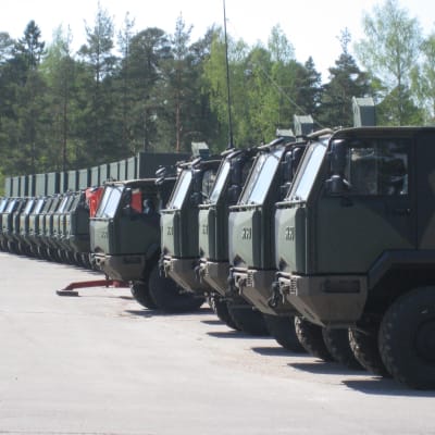 Militära Sisu-lastbilar i rad på fabrikens gårdsplan i Karis.