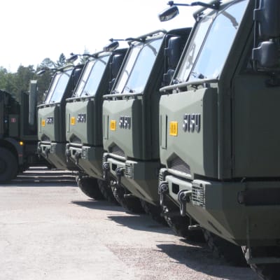 Militära Sisu-lastbilar i rad på fabrikens gårdsplan i Karis.