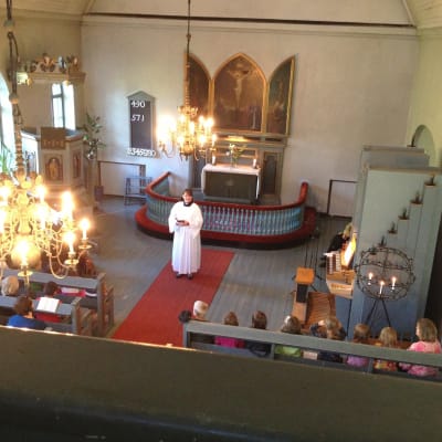 En präst håller gudstjänst i en kyrka.