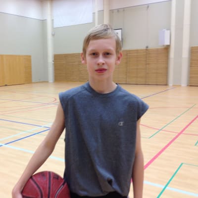 Oscar Storgård stor i en gymnastiksal med en basketboll under armen. 