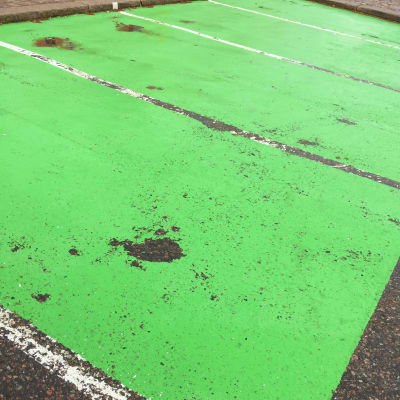 Sliten beläggning på grön parkeringsruta