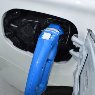 Hybridbil laddas vid en affär.