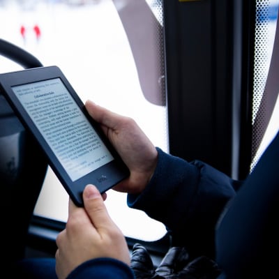 E-kirjan lukulaitteet ovat pieniä ja kevyitä. E-kirjaa luetaan linja-autossa.