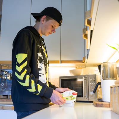 Nuori mies Miro, lämmittää mikroruokaa keittiössä