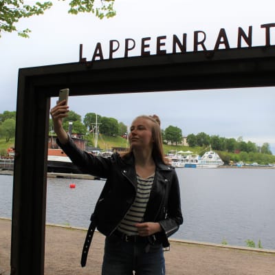 Hanna Muukkonen ottaa itsestään valokuvan Lappeenrannan maisemakehyksissä.