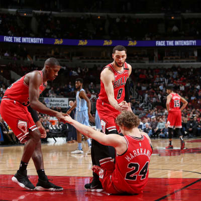 Chicago Bullsin Kris Dunn ja Zach LaVine auttavat tuskaista Lauri Markkasta ylös koripalloparketilla. 