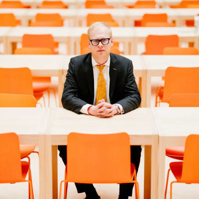 Pääanalyytikko Antti Saari istuu OP:n pääkonttorin ruokalassa, jonka tuolien väri on sama kuin konsernin logossa.
