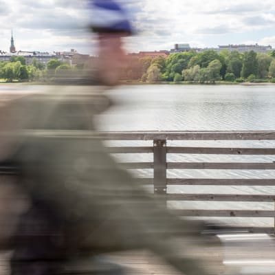 Pyöräilijä ajaa kesällä polkupyörällä sillalla Helsingissä. 