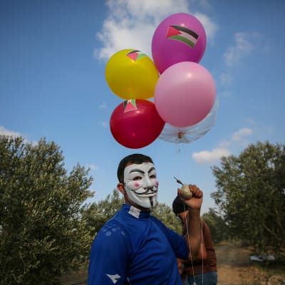 Gazassa polttopulloiskuja tekevä mies pitelee lähtövalmista ilmapallo-polttopulloa.