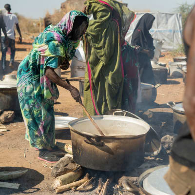 Nainen laittaa ruokaa pakolaisleirillä. 