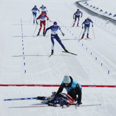 ZHANGJIAKOU, CHINA - FEBRUARY 20: Kerttu Niskanen of Team Finland crosses the finish line to win bronze as Jessie Diggins of Team United States reacts with a member of Team United States after winning silver during the Women's Cross-Country Skiing 30k Mass Start Free on Day 16 of the Beijing 2022 Winter Olympics at The National Cross-Country Skiing Centre on February 20, 2022 in Zhangjiakou, China. (Photo by Maddie Meyer/Getty Images)