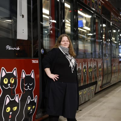 Nainen ja raitiovaunu, jossa on kissankuvia.