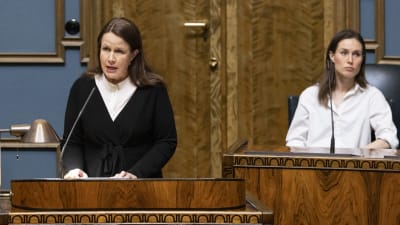 Veronika Honkasalo i riksdagens talarstol, bakom henne statsminister Sanna Marin.