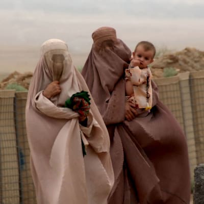 Två kvinnor i burqa bär sina barn i Khakrez, Afghanistan.
