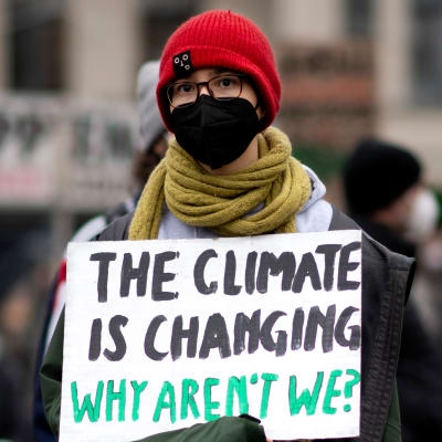 Collage av två bilder. Till vänster en bil som kör förbi en bensinstation, till höger en person som håller i en skylt där det står "The climate is changing, why aren't we?".
